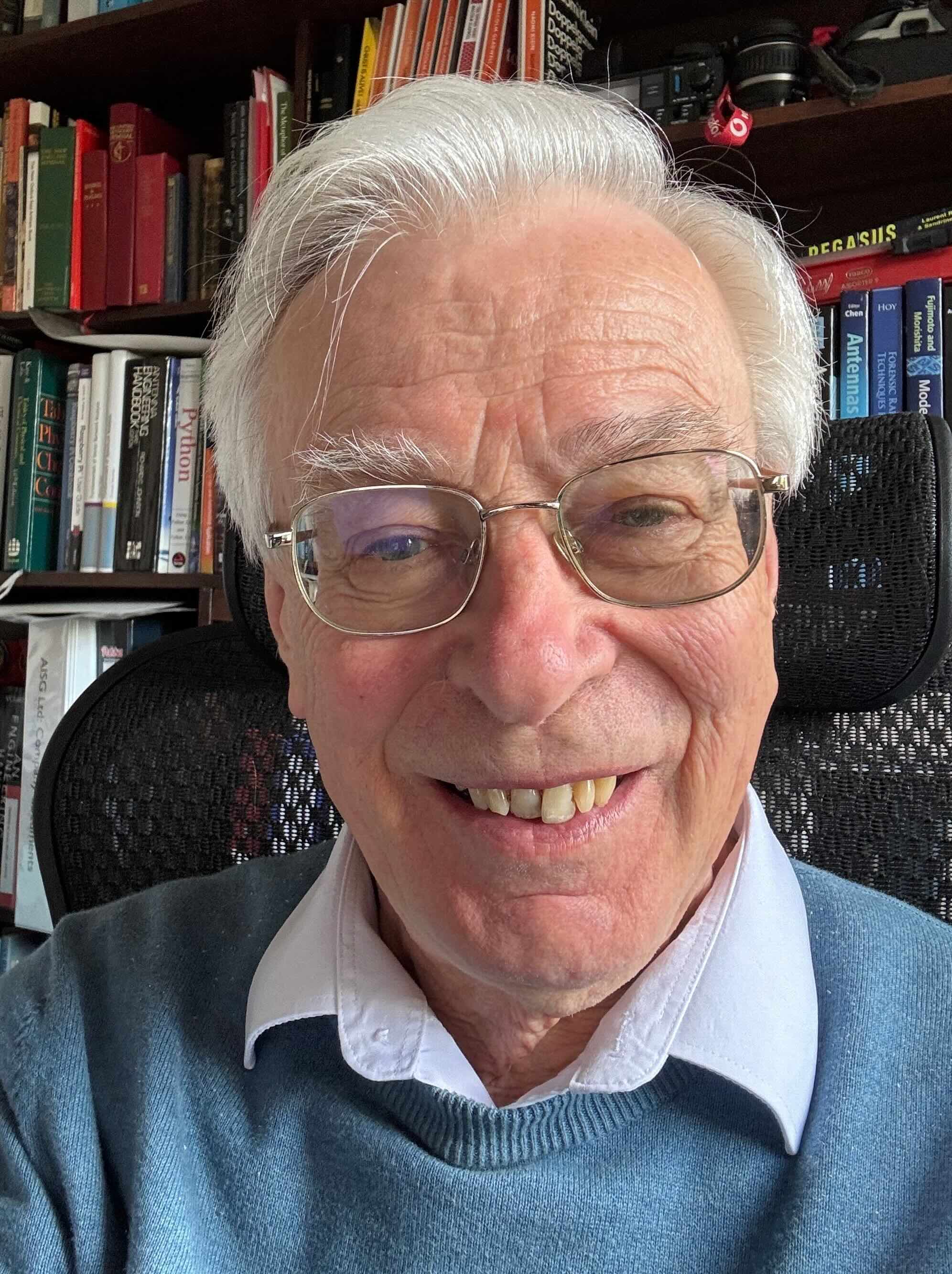 Brian Collins, founder of BSC Associates, photographed in his library of antenna‑engineering reference books.