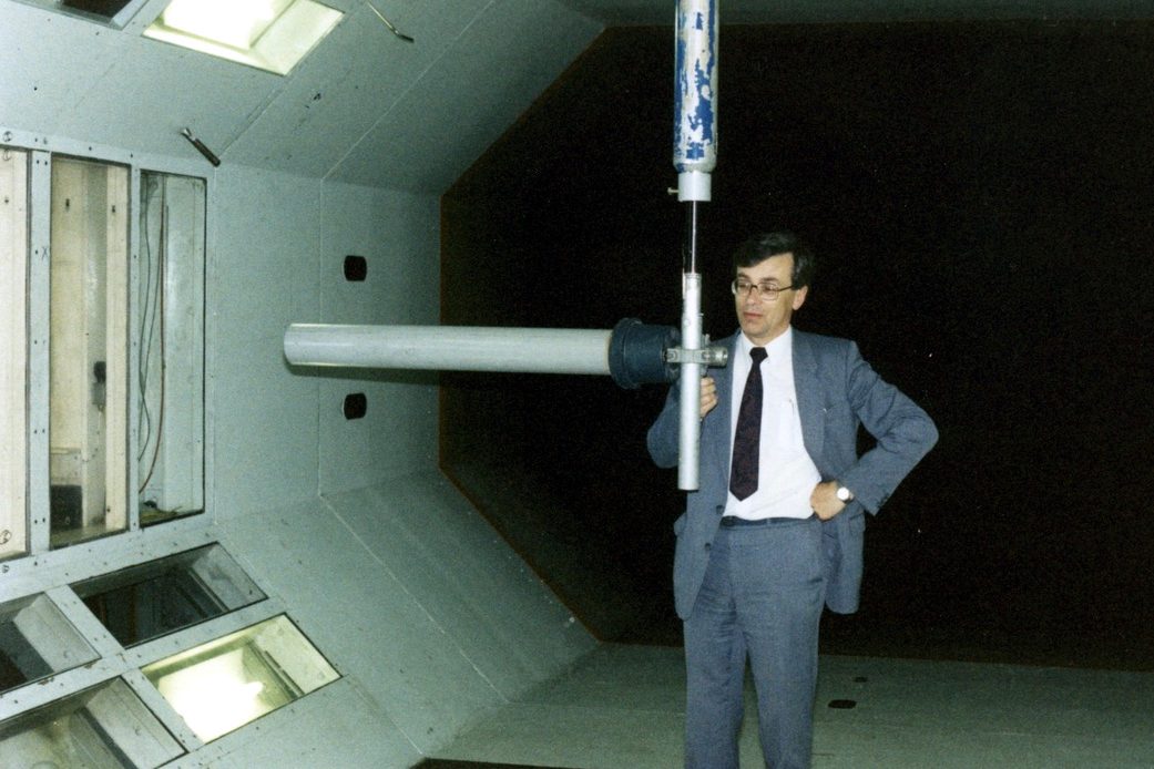 Brian Collins standing beside an antenna on a mast inside a wind tunnel