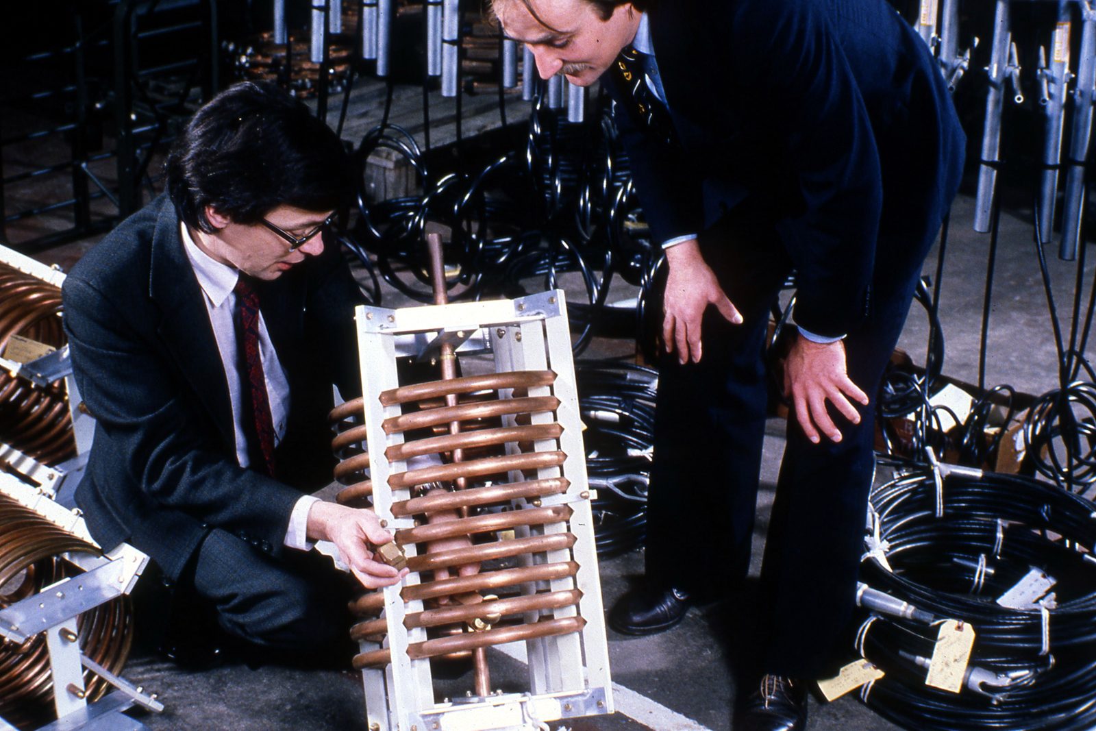 Brian Collins and a colleague examining a large copper coil in a factory