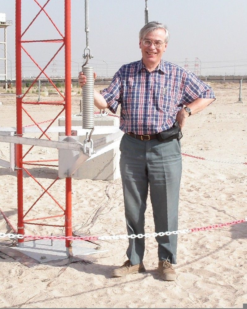 Brian Collins standing at the base of a red lattice mast in the desert