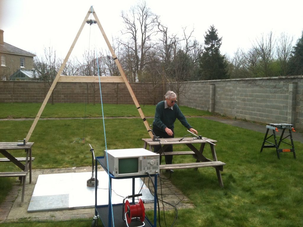 Brian Collins at an outdoor antenna test range with a wooden A‑frame, groundplane and network analyser