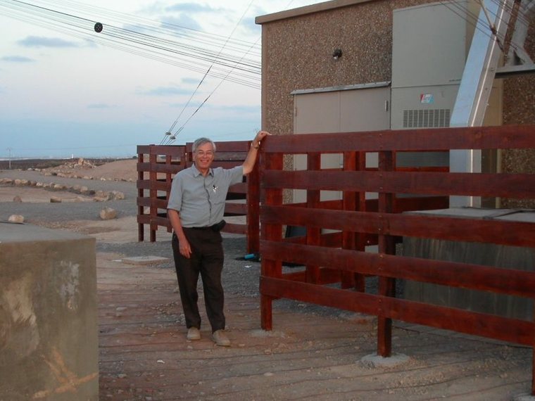 Brian Collins beside a transmitter building with feeder lines overhead