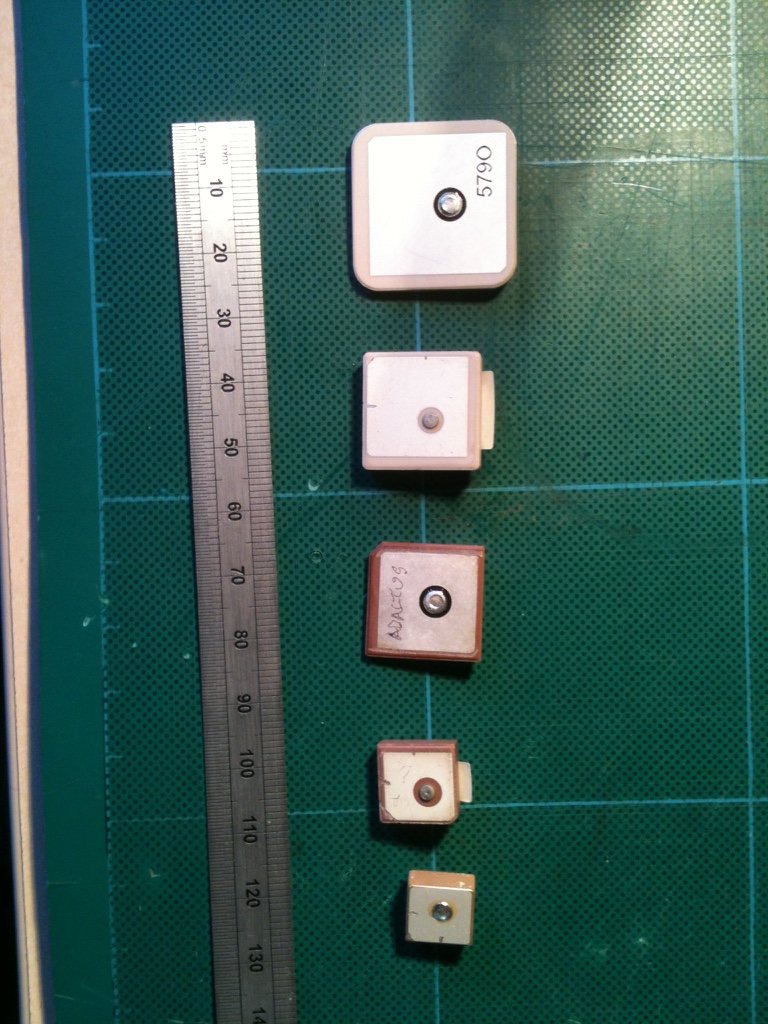 Five square ceramic patch antennas of decreasing size beside a steel rule marked in millimetres